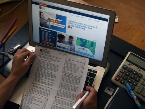 Persona con un computador y un documento del Servicio de Impuestos Internos (SII)