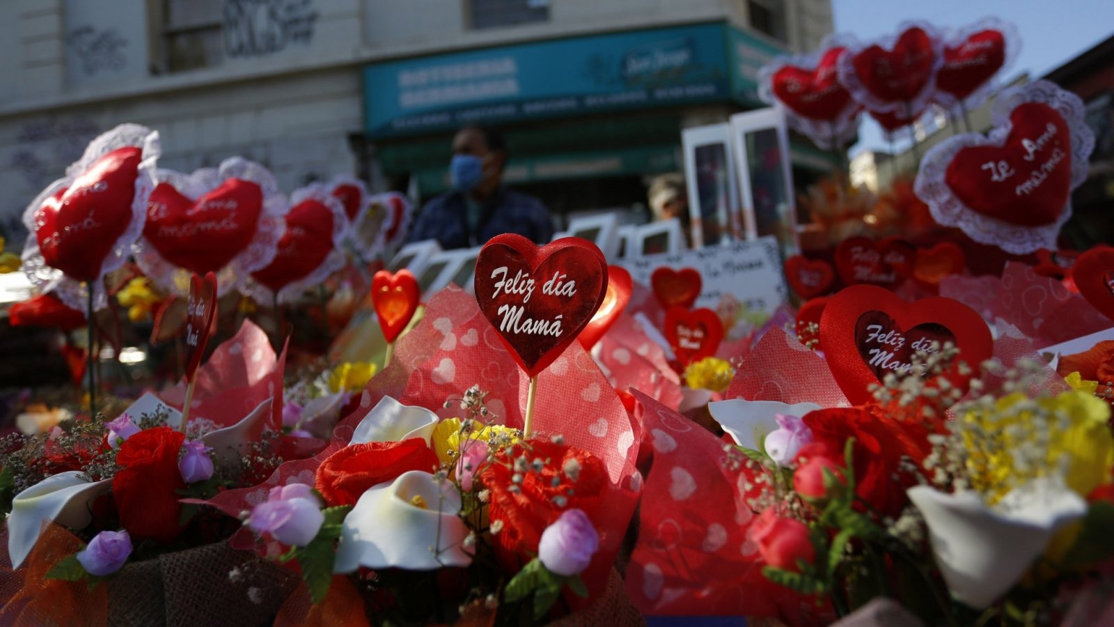 Flores y corazones rojos con la frase "feliz día mamá".