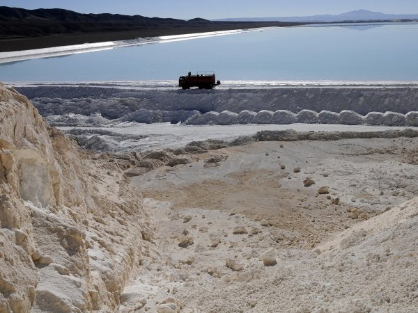 Salar con un lago de fondo y un camión de transporte pasando.