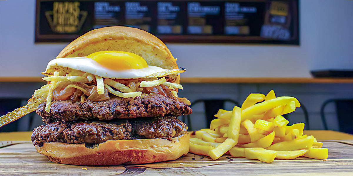 Hamburguesa a lo pobre con papas fritas a un costado.