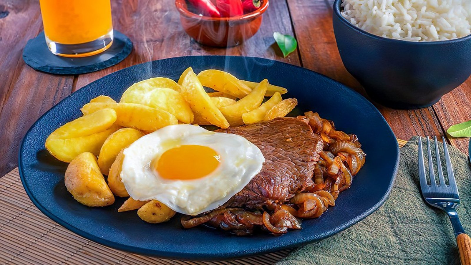 Plato de bistec a lo pobre con carne, cebolla, huevo y papas fritas.