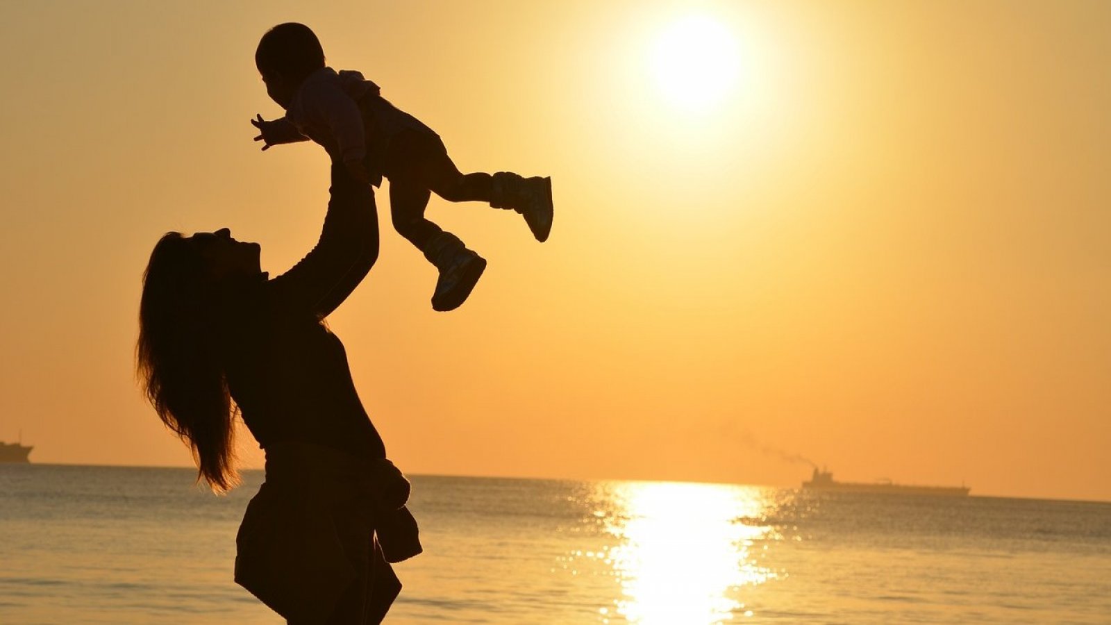 Madre alzando a su hijo en medio de la playa