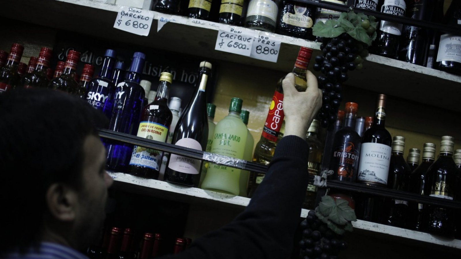 Hombre mostrando las botella de alcohol de una botillería