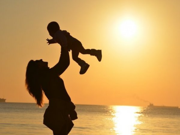 Madre alzando a su hijo en medio de la playa