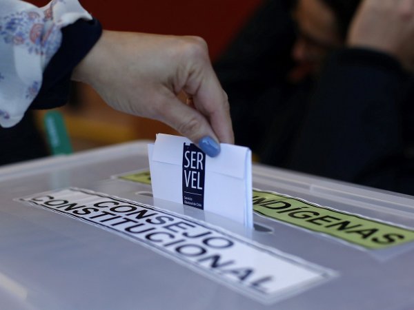 Mano de una persona ingresando su voto en una urna electoral