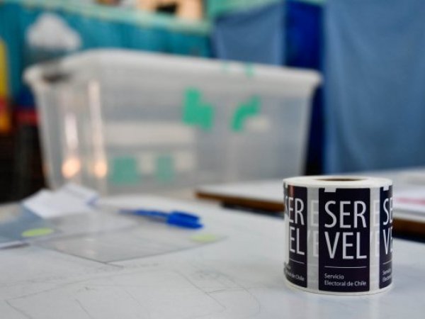 Sticker del Servel al lado de una urna de votación.