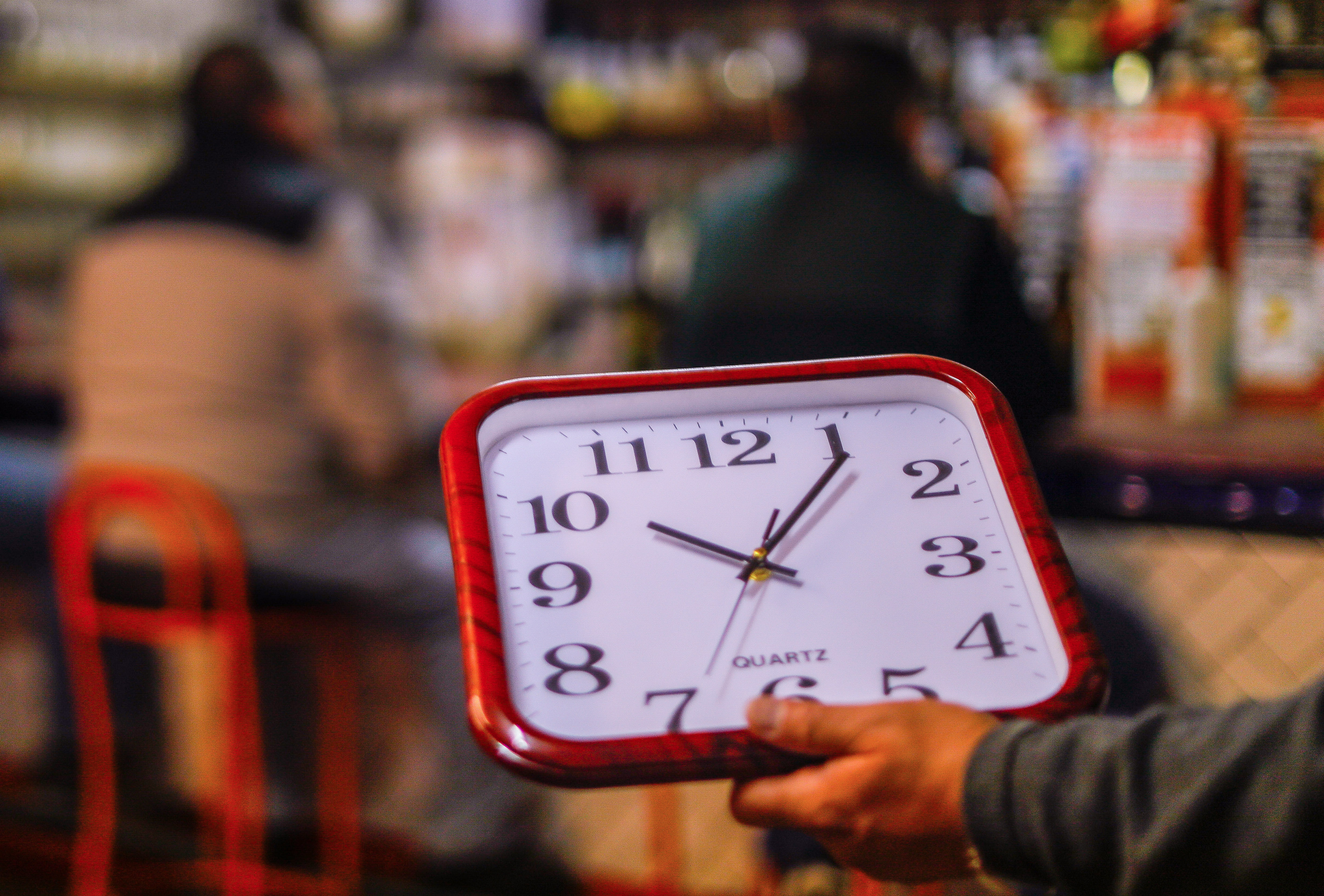 Reloj de pared en la mano de una persona.