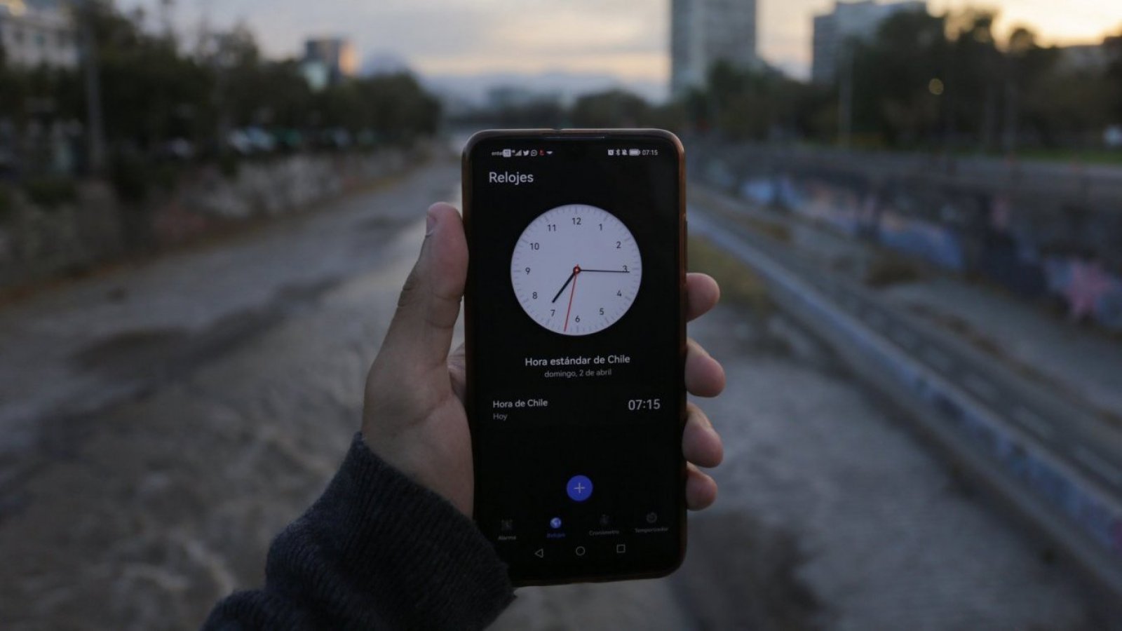 Persona con el reloj en un celular en la mano. Hora oficial.