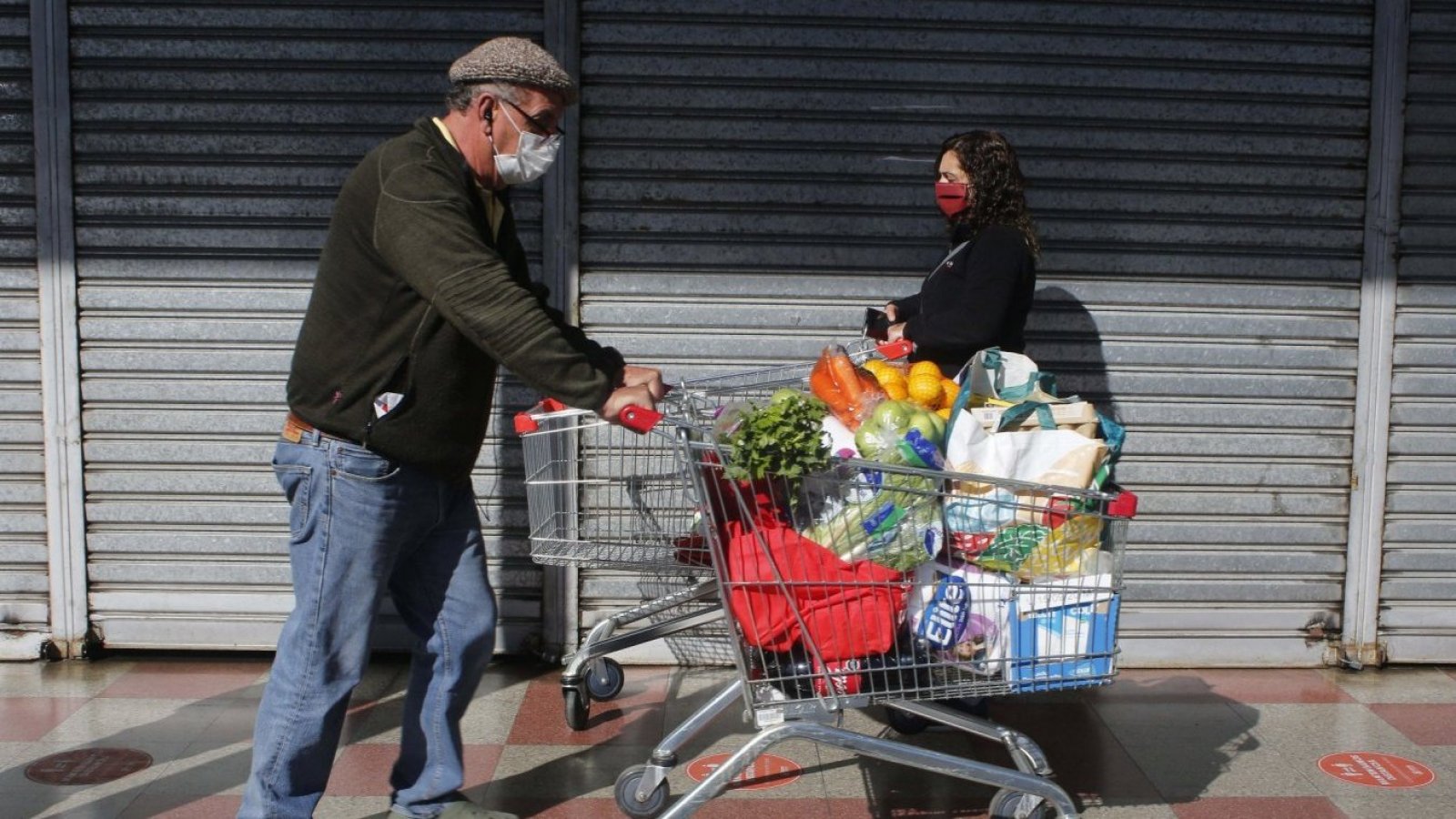 Adultos comprando con carros de supermercado.