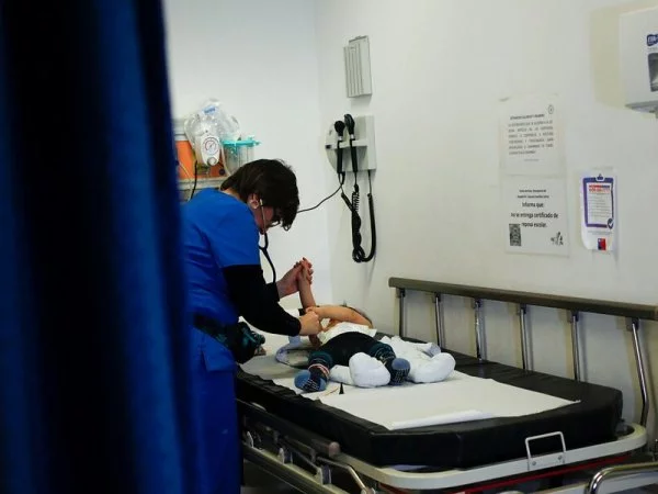 Enfermera atendiendo a un bebé con virus sincicial en una camilla de hospital.