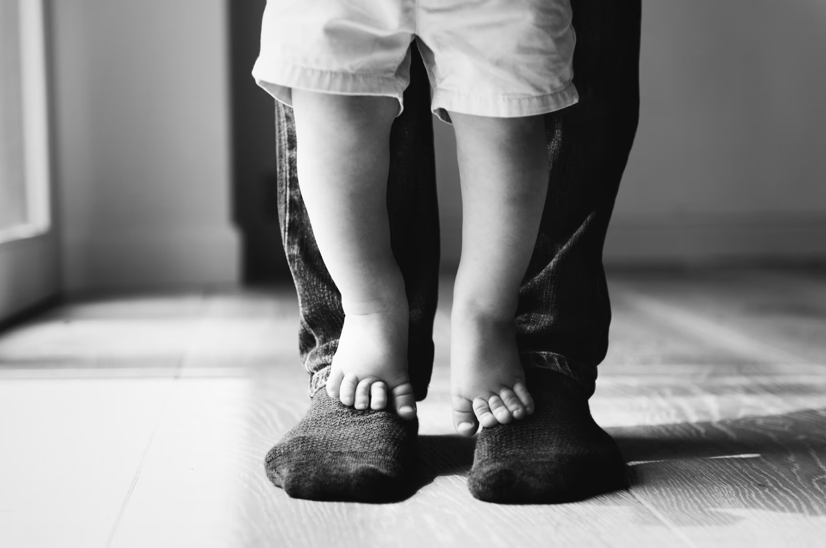 Niño parado en los pies de su padre