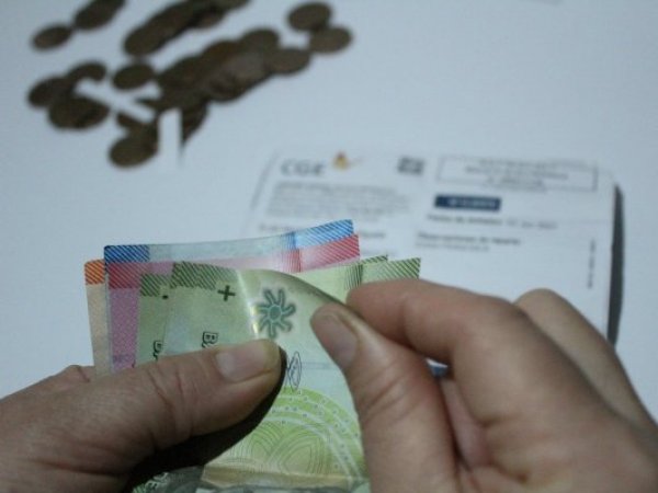 Persona contando dinero en sus manos y cuentas de fondo.