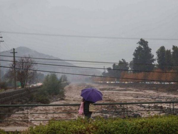 Persona bajo la lluvia mirando un río.