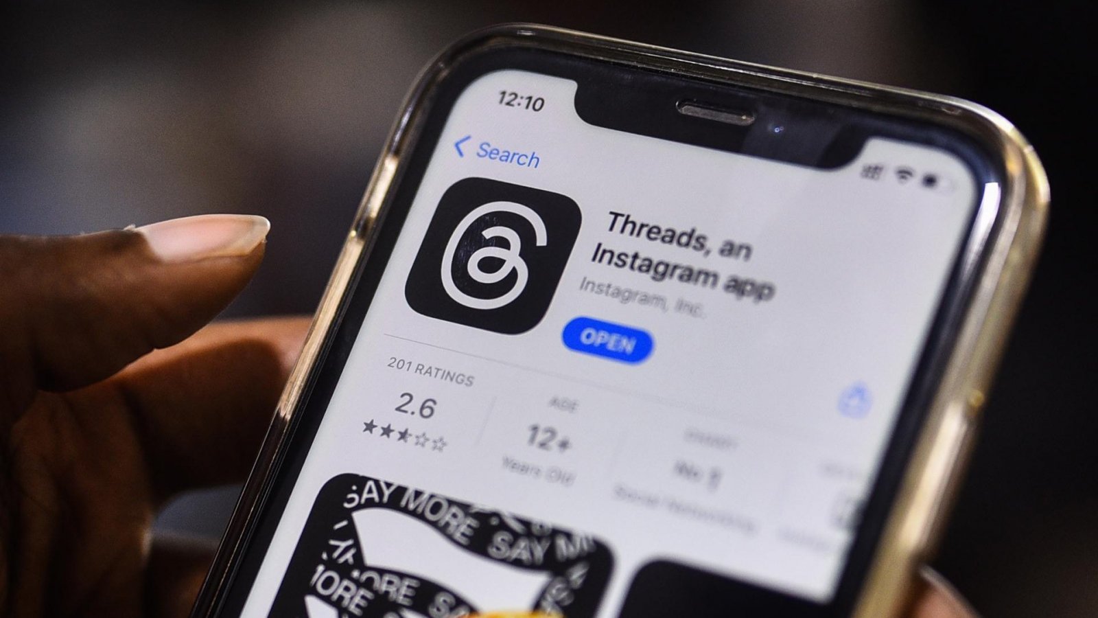 Mano sujetando un teléfono descargando la app de Threads.
