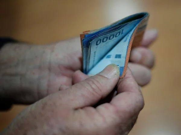 Mano sujetando billetes de diferentes montos.