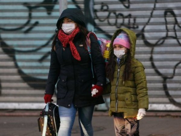 Mujer caminando con una niña en el frío.