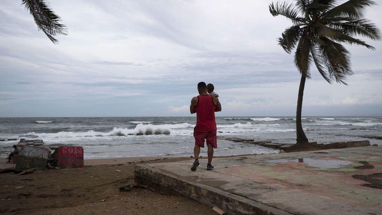 Una persona sostiene a un niño frente a una playa