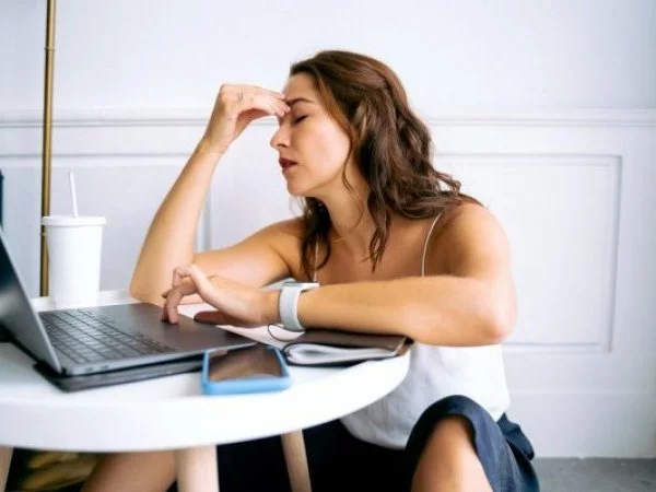 Cambio de hora. Mujer con dolor de cabeza en el trabajo.