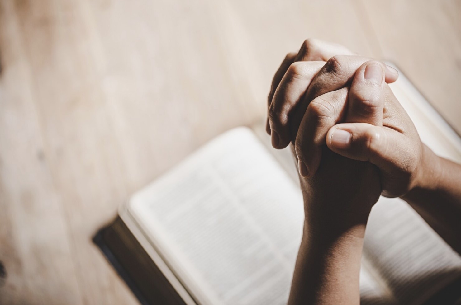 Manos rezando ante una biblia. Bendiciones para un abuelo o abuela.
