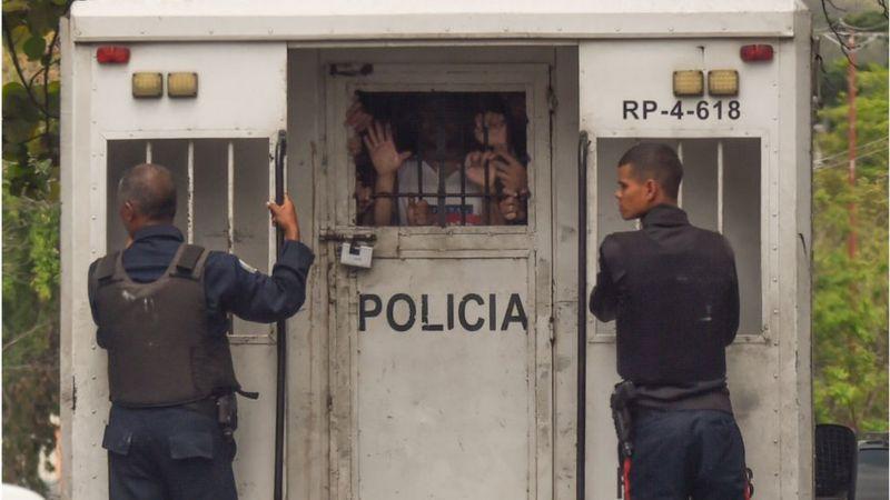 La policía lleva a detenidos en diferentes unidades de transporte.