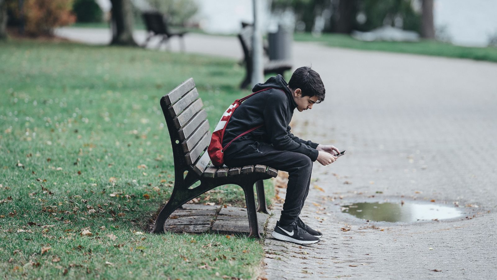 Adolescente utilizando redes sociales en una plaza solo