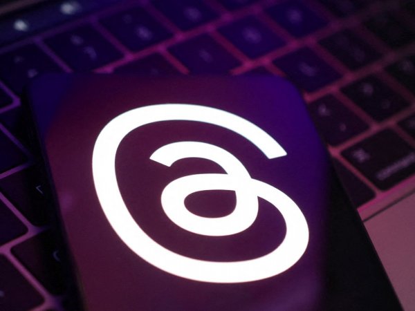 Logo de Threads en un celular sobre un computador. Threads web.