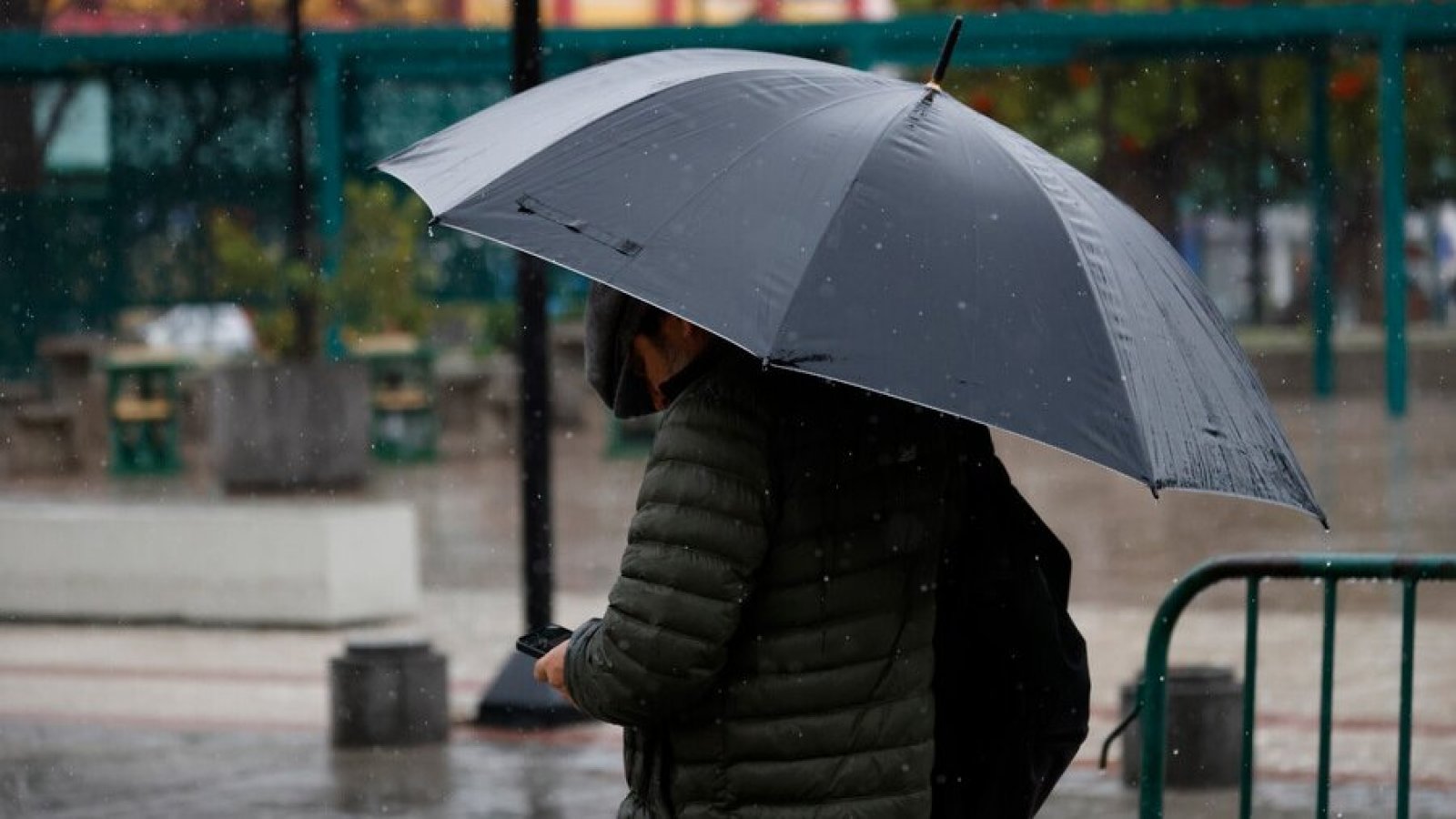 Persona bajo la lluvia con paraguas. Advertencia por lluvias Meteorología.