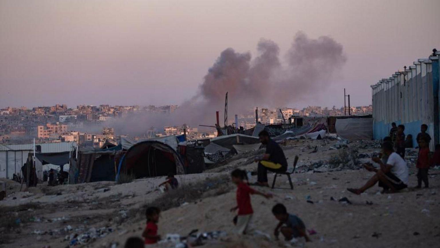 Adultos y niños, junto a tiendas de campaña en un atardecer en Gaza. 