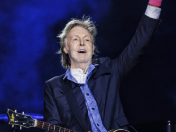 Paul McCartney con una guitarra elevando el puño de su mano
