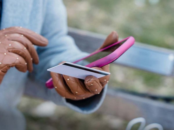 Persona usando una aplicación de banca digital desde su celular en un café.