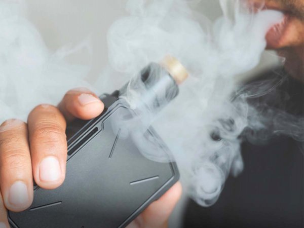 Niño inhalando humo de un cigarrillo electrónico, reflejando los riesgos que implica el uso temprano de estos dispositivos.