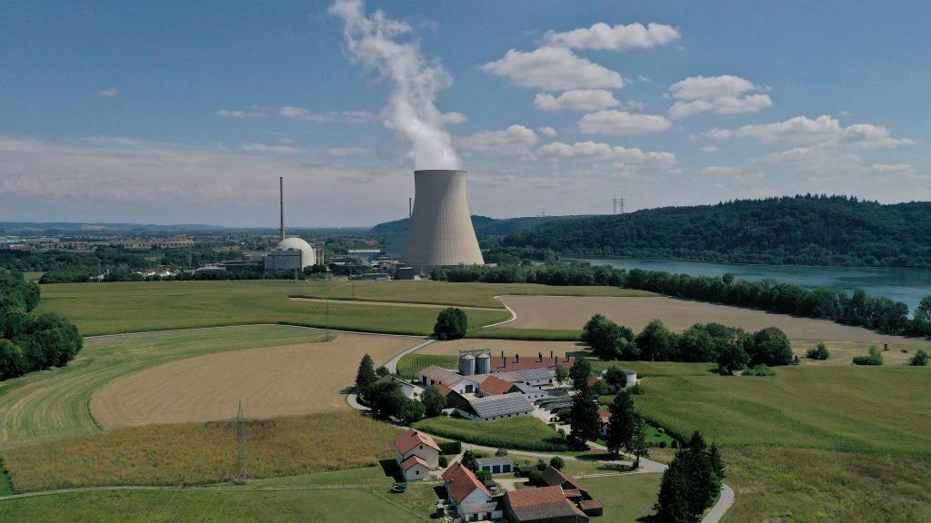 Una central nuclear al lado de un río y un pequeño pueblo