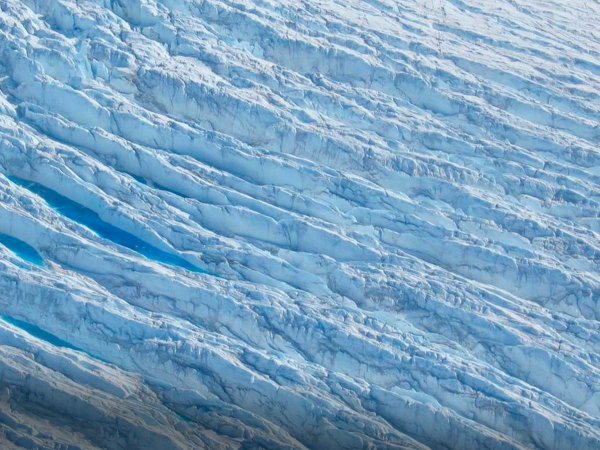 Vista aérea de grietas en la capa de hielo de Groenlandia, evidenciando el impacto del cambio climático.