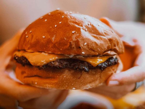 Niño frente a una mesa con alimentos ultraprocesados como hamburguesas, papas fritas y bebidas azucaradas.