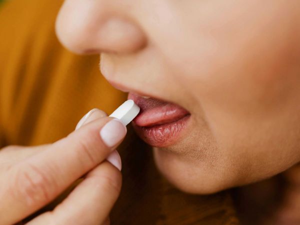 Mujer tomando pastilla. Referencial.
