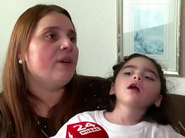 Valeska, madre de Trinidad, sentada con ella en brazos hablando frente a cámara