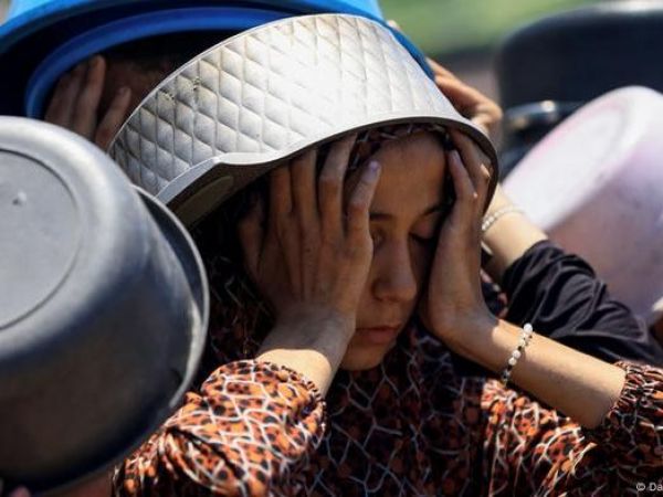 Mujer con un recipiente en la cabeza y sus manos en la cara en modo de desesperación.