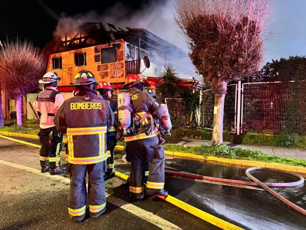 Bomberos en casa consumida por las llamas.