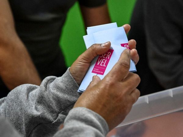 Persona sujetando votos electorales del Servel en sus manos