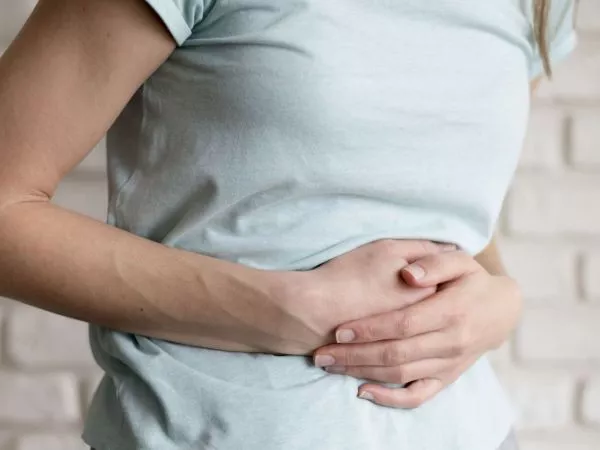 Persona tomándose su estómago demostrando dolor.