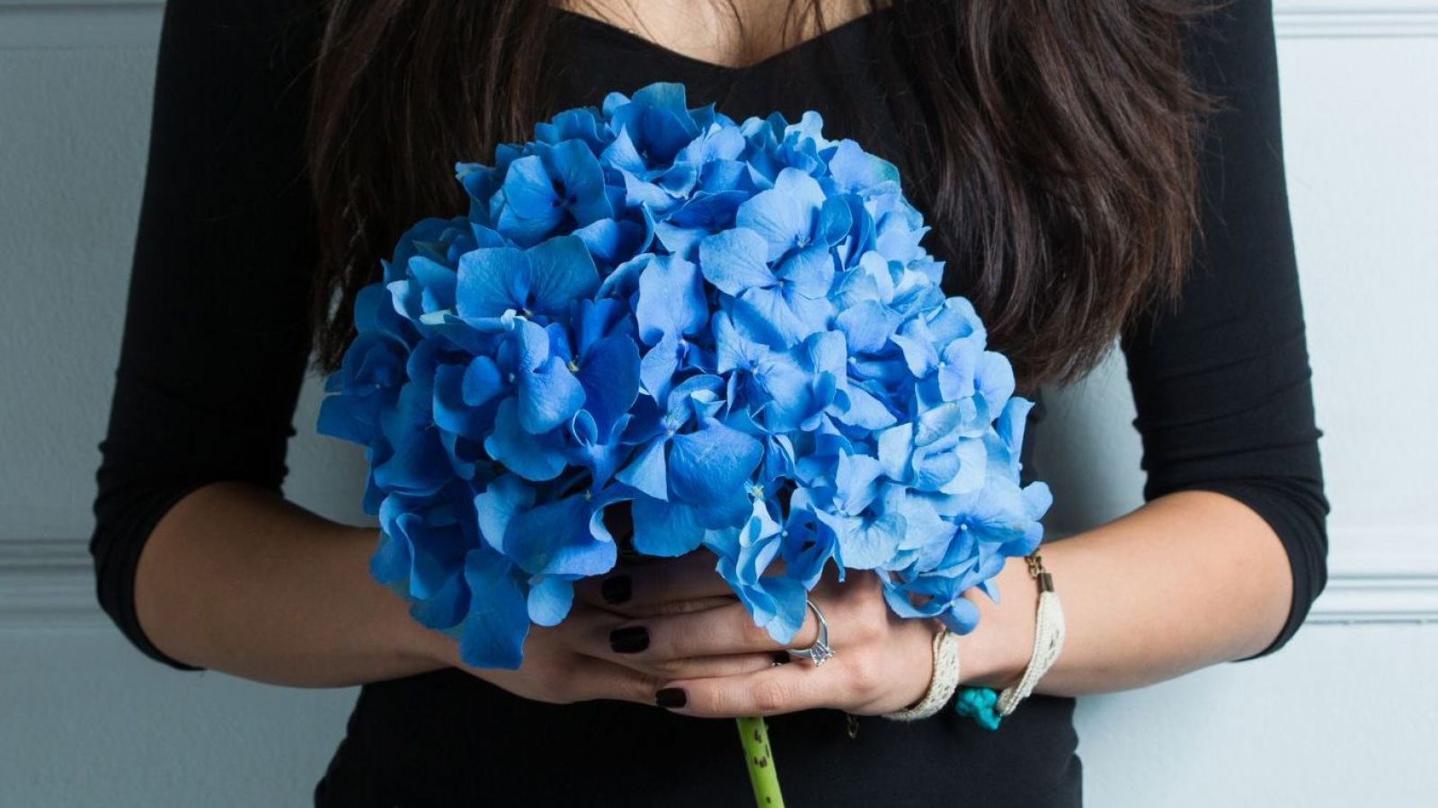 Manos de mujer con un ramo de flores azules.