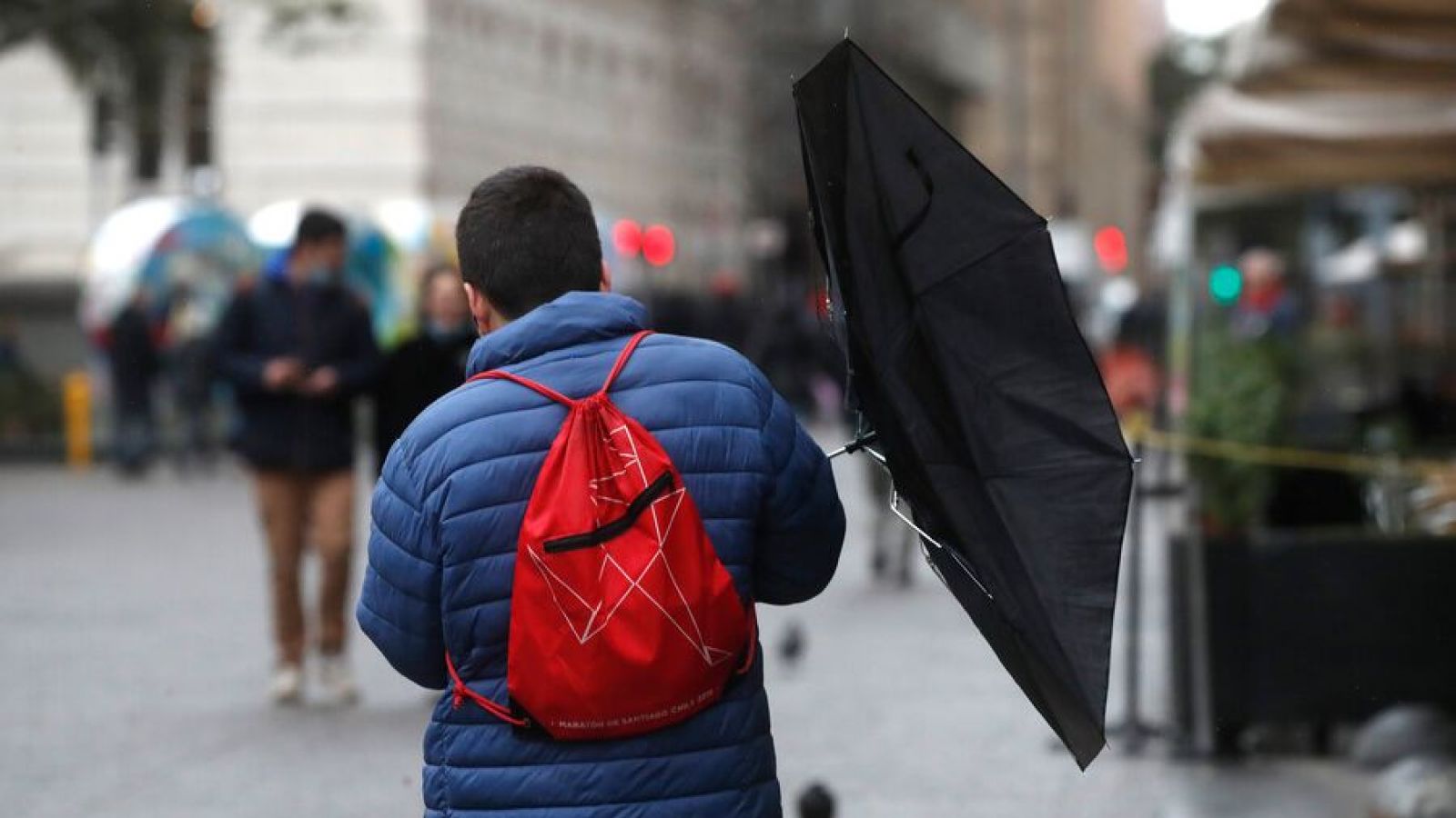Persona caminado con paraguas y viento