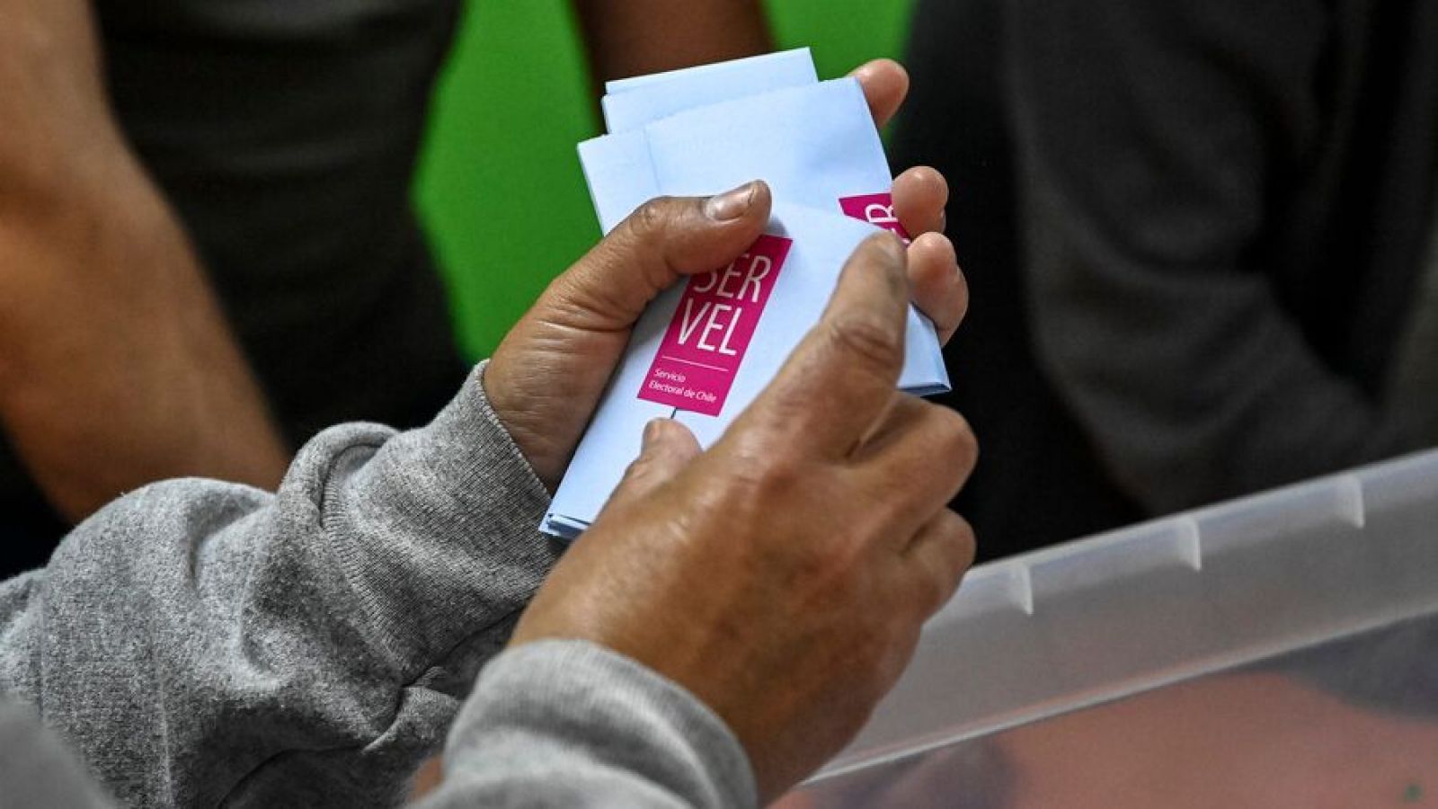 Mano sujetando voto con sticker del Servel en elecciones