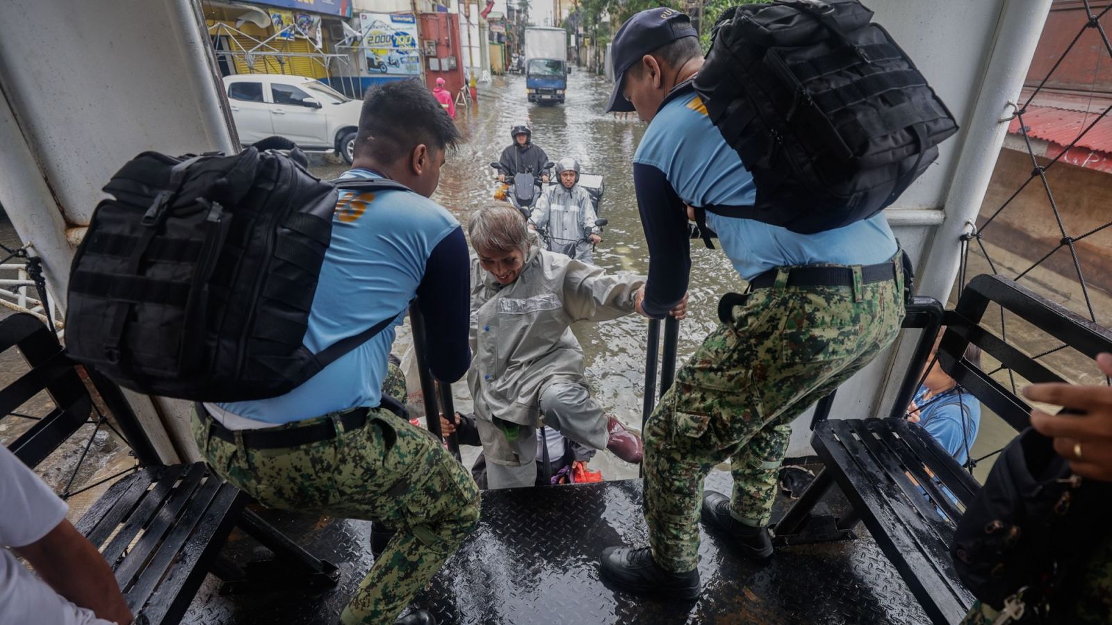Dos personas con uniformes oficiales ayudan a damnificados en el paso del tifón en Filipinas.