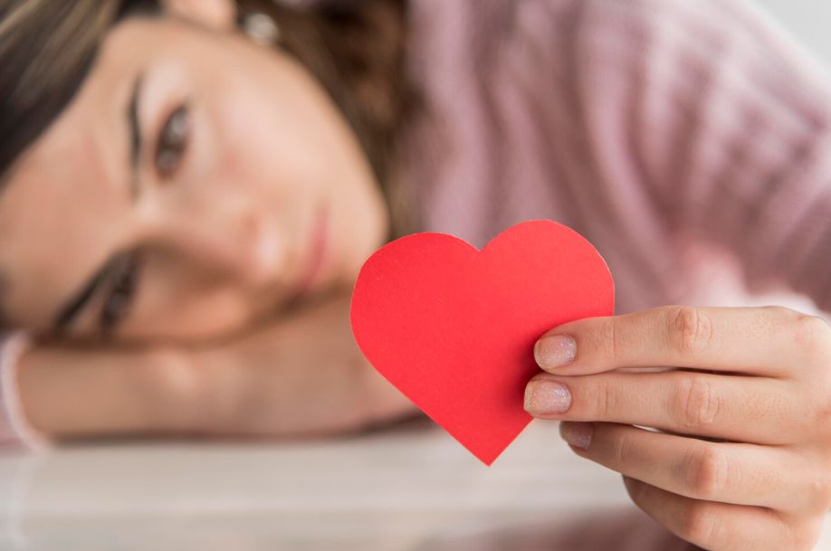 Mujer triste sujetando un corazón de papel