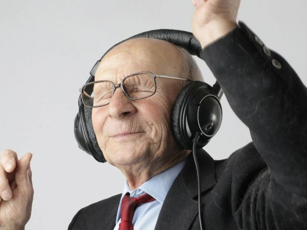 Persona adulta mayor escuchando música con audífonos como estimulación cognitiva.