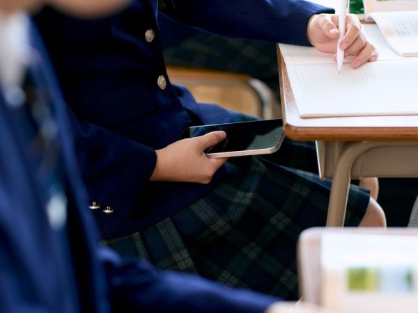 Niña con celular en la sala de clases
