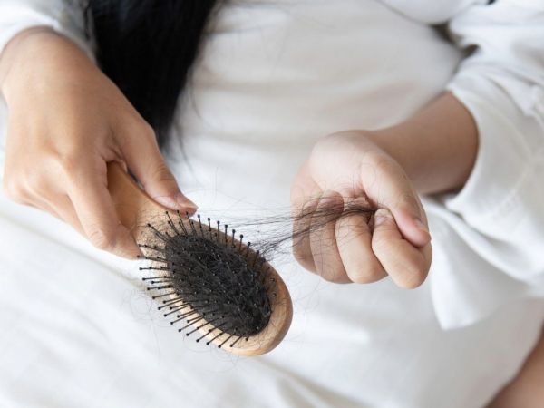 Una mujer sostiene un cepillo quitándole el pelo que se quedó enredado