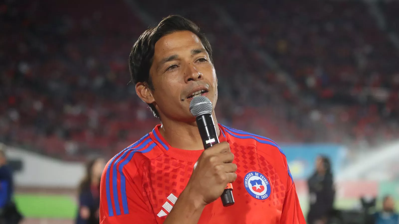 Matías Fernández hablando en un estadio con un micrófono