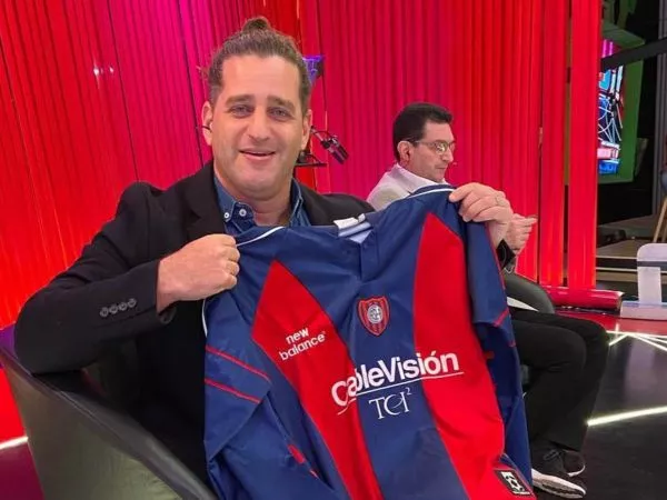 Damián Manusovich posando con una camiseta de San Lorenzo